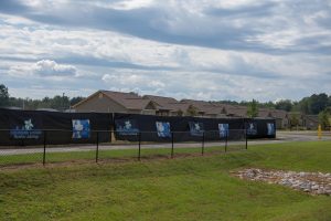 The site for the Assisted Living Center is currently surrounded by a black-mesh fence covering. It will be adjacent to the cottage development, across the road from the hospital.